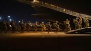 An A-29B Super Tucano flies over Mauritanian Army soldiers as they pose for a picture in Atar, Mauritania, Feb. 17, 2020, during Flintlock 2020, U.S. Africa Command's largest annual special operations forces exercise.